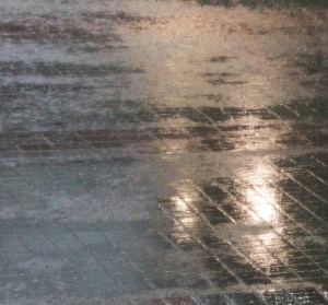 Background lights reflect off watery pavement