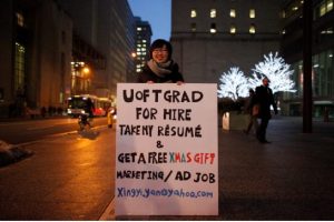 University grad Xingyi Yan, 21, has taken a placard to the street in a bid to land a job in advertising or marketing. (Credit: MARTA IWANEK / TORONTO STAR)